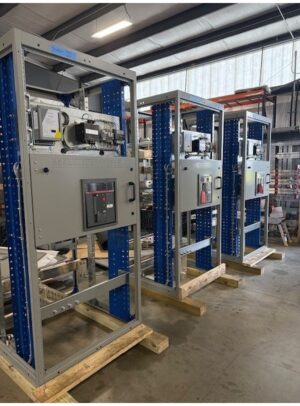891Switchboard - ABB Multiple Mains - Coastal Power Systems Row of industrial control cabinets mounted in blue steel frames on a factory floor, ready for installation.