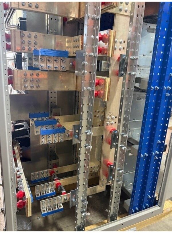 891Switchboard - CPSafe Blue and Bus - Coastal Power Systems Inside an industrial electrical cabinet showing metal frames, busbars, and red terminal connections.